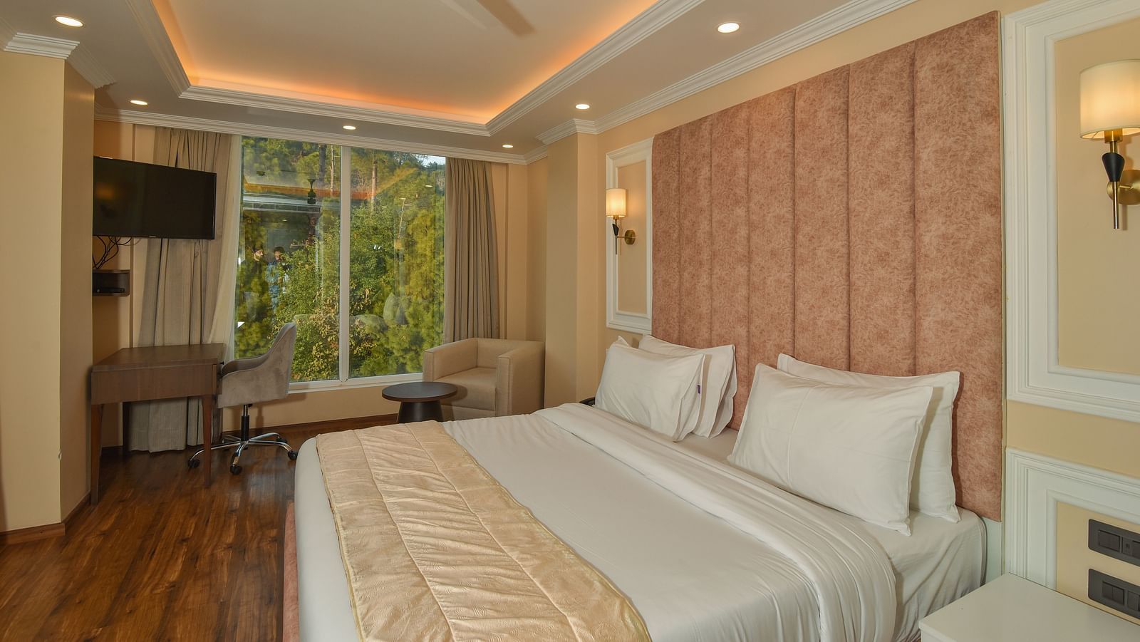 A modern hotel room with a comfortable double bed, stylish decor, and large windows offering views of the surrounding landscape. The room is bright and spacious, perfect for relaxation.