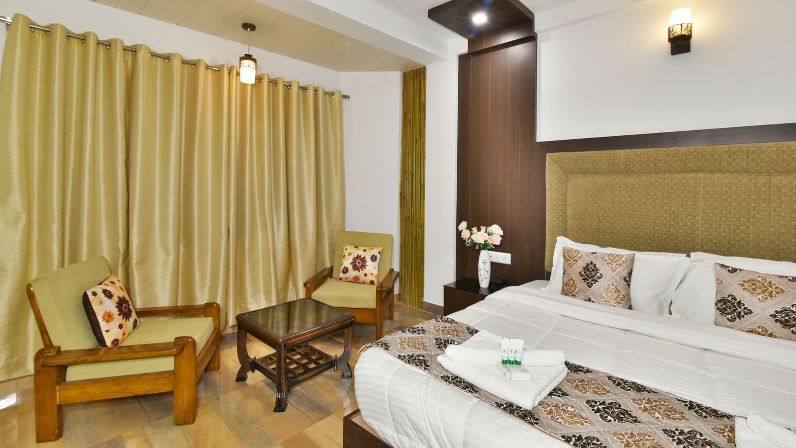 A side angle shot of a room that showcases the king size bed and the cosy seating arrangement | DLS Kapoor Resort Manali