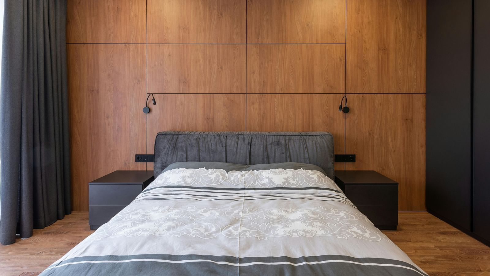 A bedroom with a king size bed with side tables on either side and a wardrobe