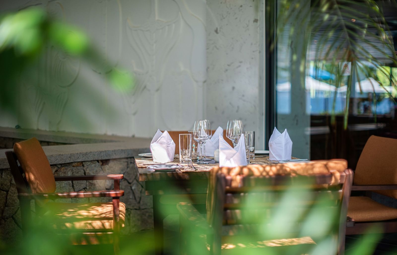 An outdoor sitting area with wooden chairs and tables- Alibu Resorts Nha Trang