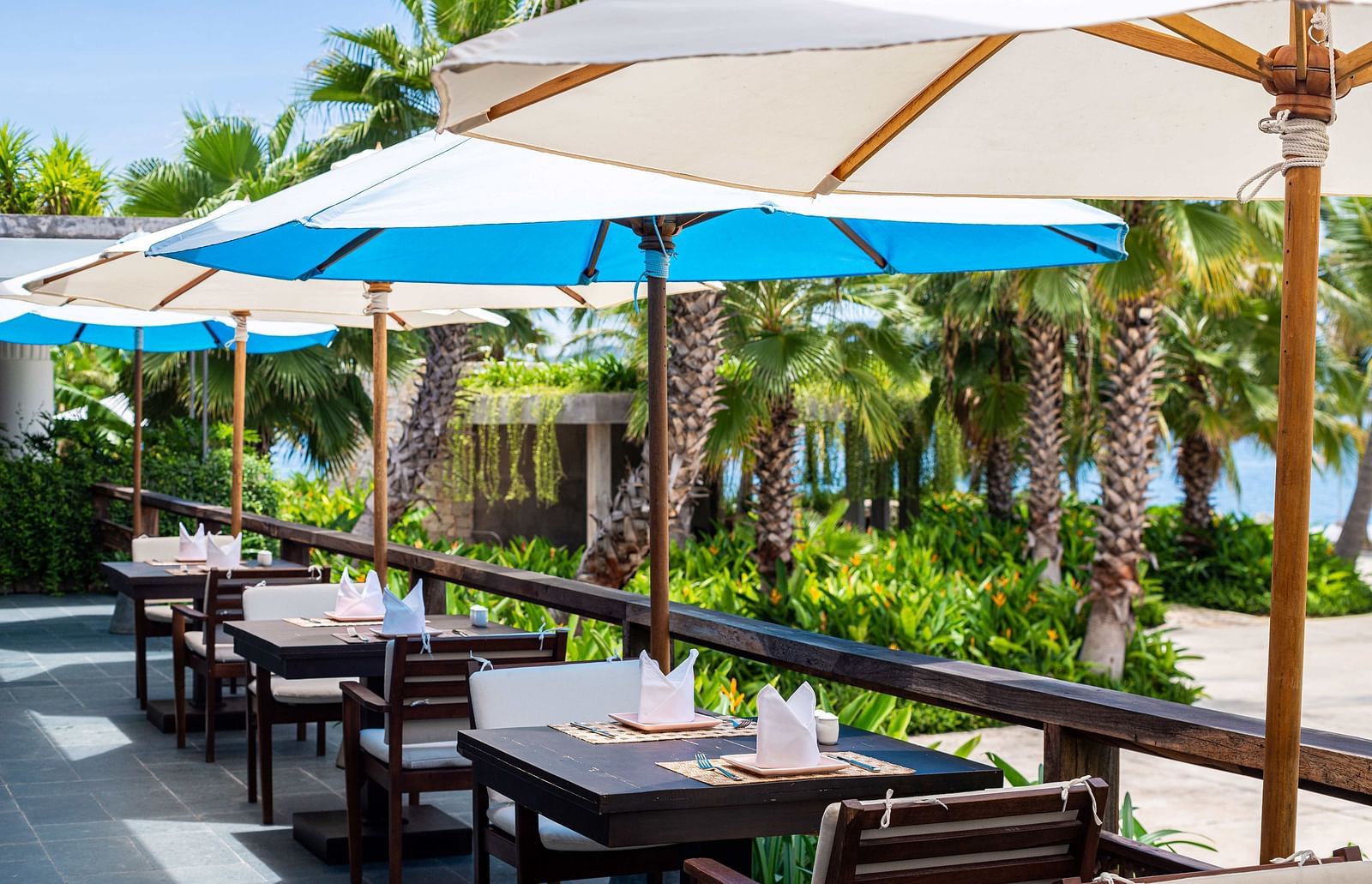 An outdoor sitting area with wooden chairs and tables - Alibu Resorts Nha Trang