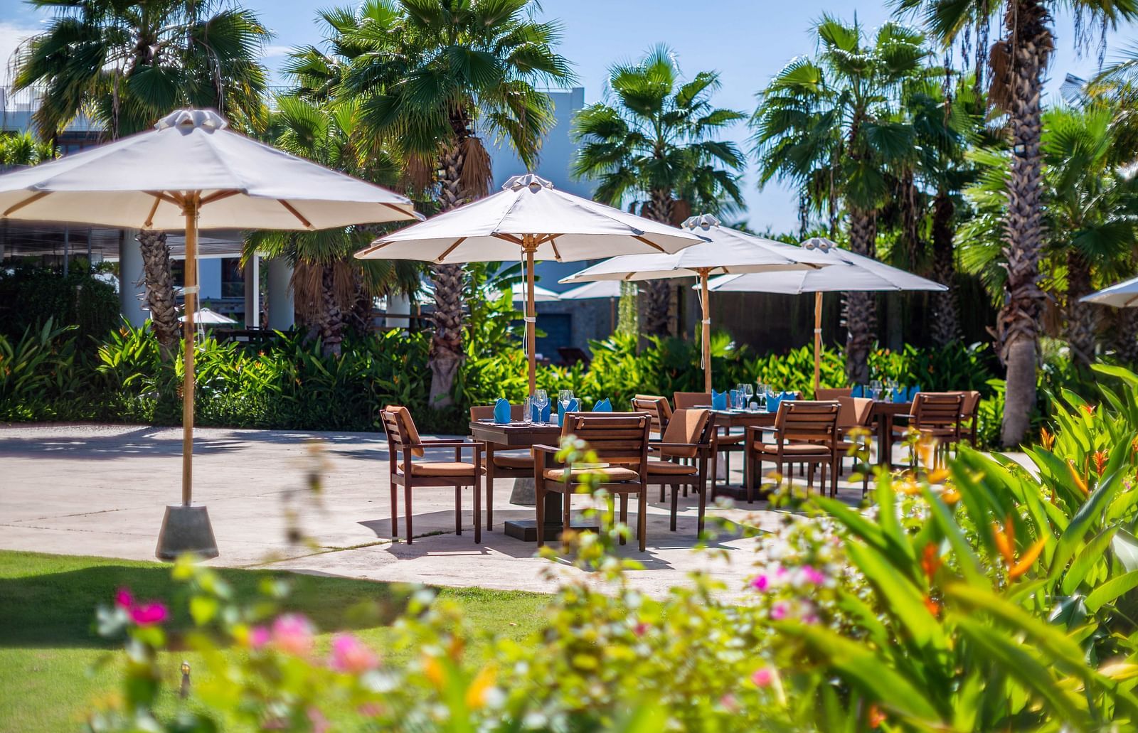 A garden side view of a seating arrangement placed in a veranda with sun shades to protect from sun - Alibu Resort Nha Trang 