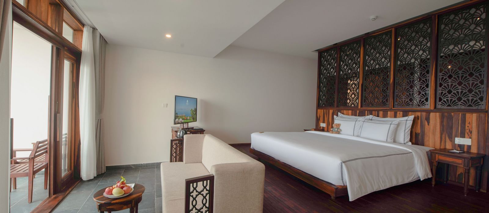 A hotel room with a balcony, plenty of amenities and a sofa facing towards the balcony - Alibu Resort Nha Trang