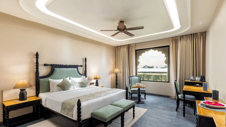 A luxurious bedroom at Beelwa Palace, Jaipur features an elegant 4-poster bed, stylish decor, and a cosy ambience.