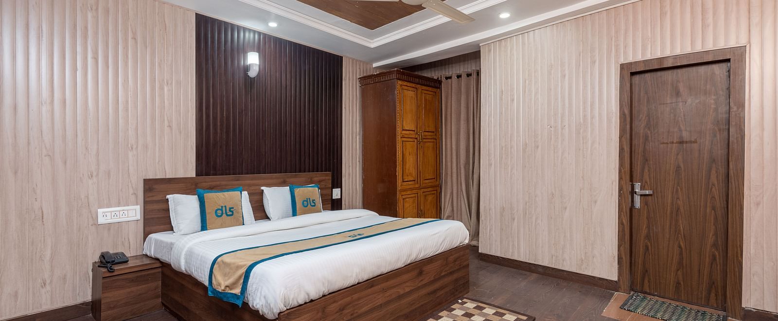A wide angle shot of a king size bed in the a room with wooden flooring  | DLS Anupam Resort, Dharamshala