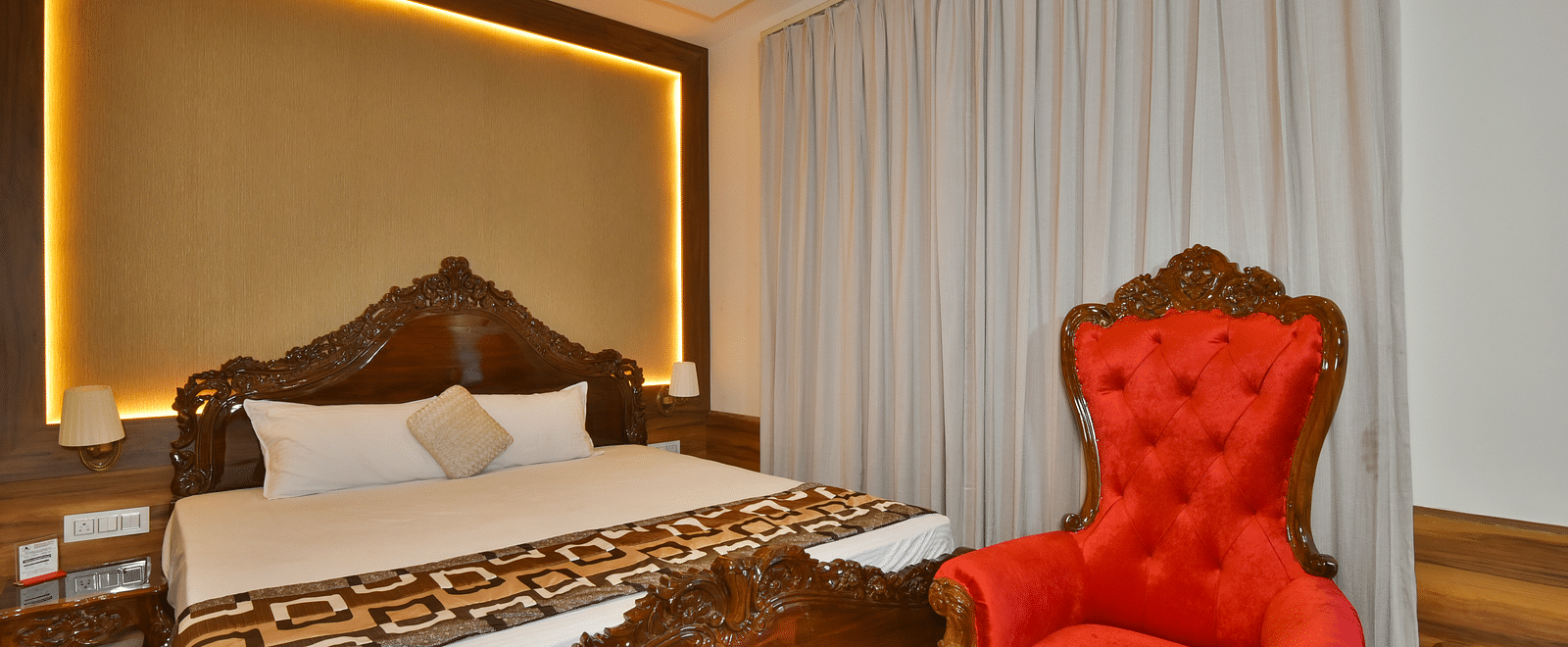 Super Deluxe room at DLS Dalhousie Valley Resort with a  king size bed, a chair and warm lighting 