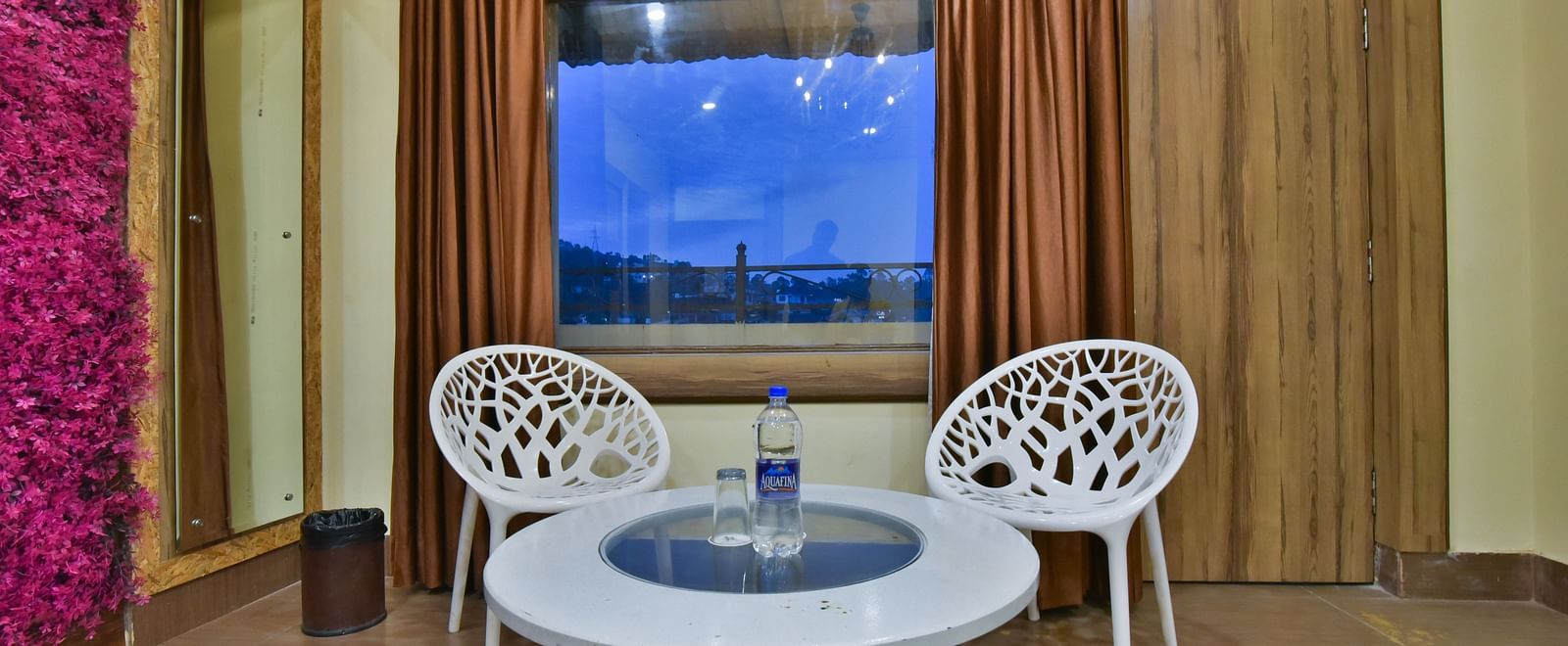 Sitting area of a Family Suite at DLS Dalhousie Valley Resort featuring chairs, table and a window. 