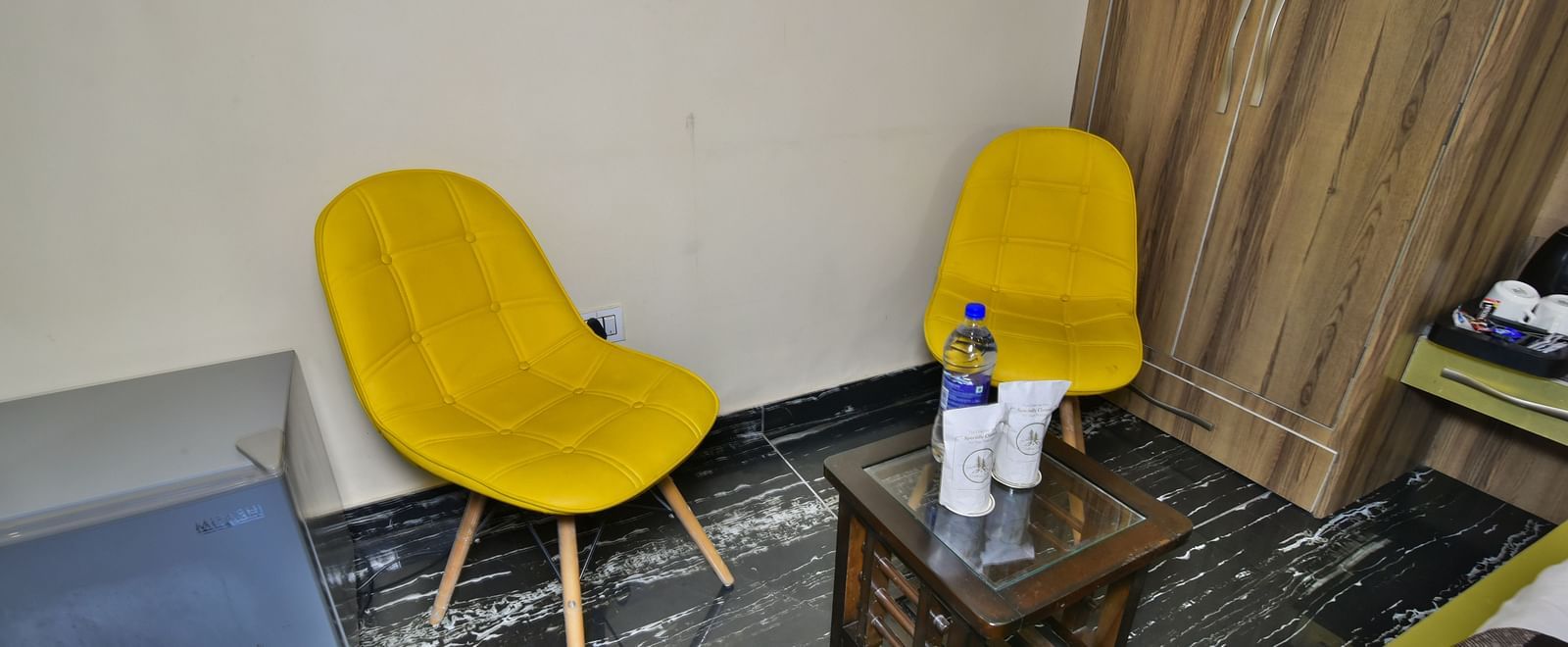 Sitting area of a Deluxe Room at DLS Dalhousie Valley Resort with yellow chairs and a table.