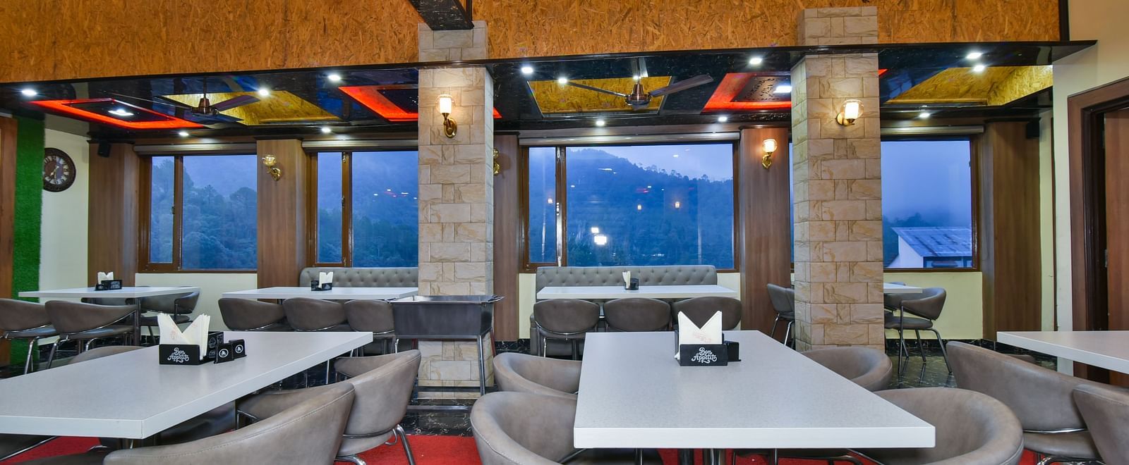 Restaurant at DLS Dalhousie Valley Resort with chairs, tables, ambient lighting and serene views