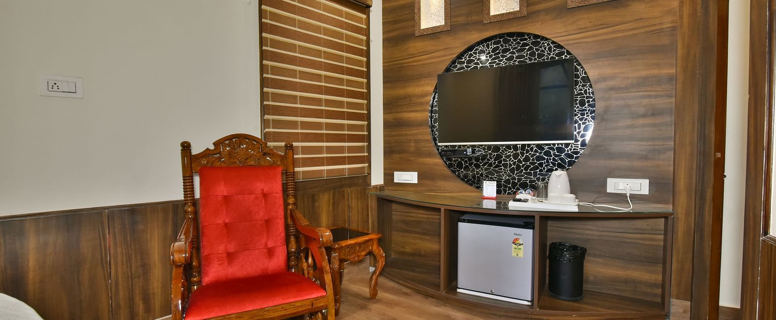 Sitting area of a Deluxe Room at DLS Dalhousie Valley Resort with a red chair, mirror and a table.