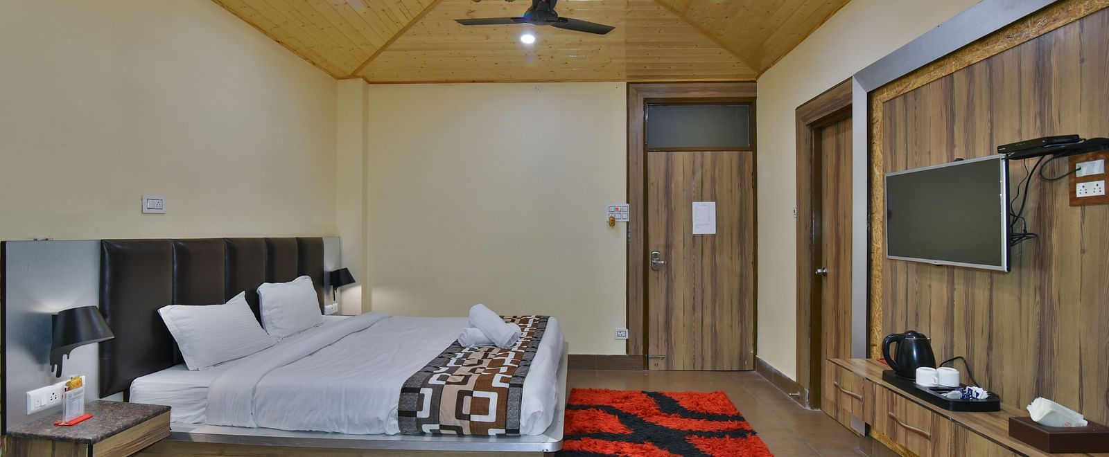 Family Suite at DLS Dalhousie Valley Resort with a king size bed, a table, chandelier and a TV. 