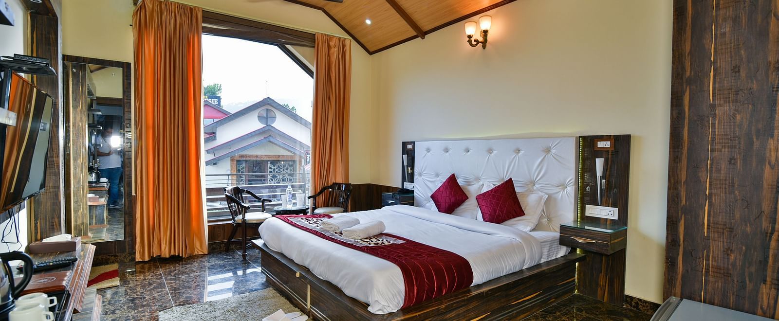 A Deluxe Room at DLS Dalhousie Valley Resort with a  king size bed, TV and a balcony 