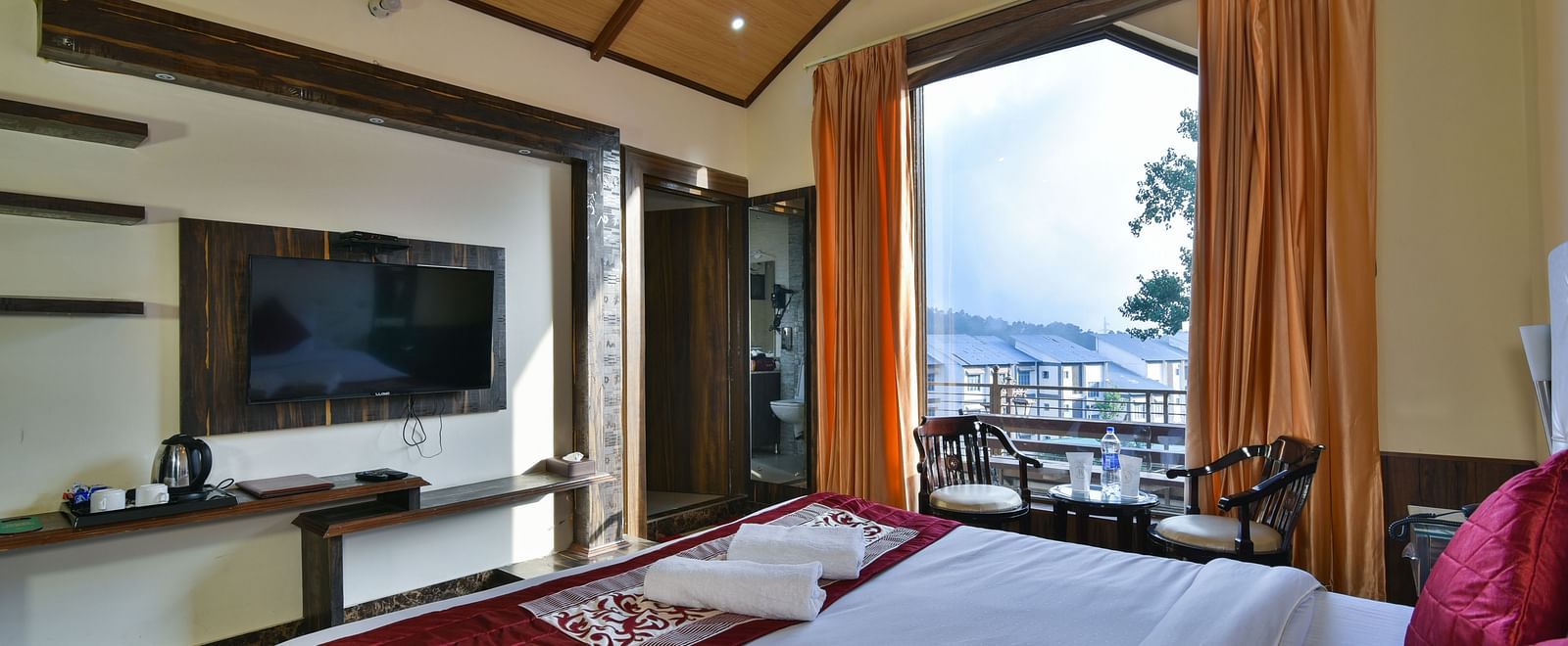 A Deluxe Room at DLS Dalhousie Valley Resort with a  king size bed and a balcony.