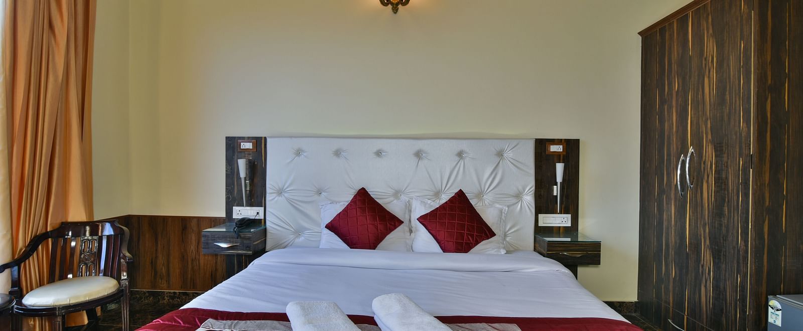 A Deluxe Room at DLS Dalhousie Valley Resort with a king size bed, a chair and ambient lighting. 