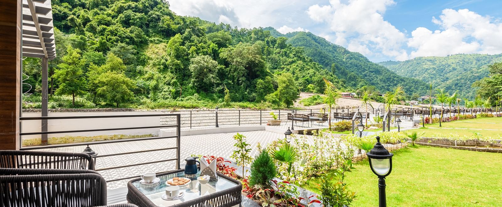Closeup view of the balcony of Luxury Cottage at DLS Divine Resort and Spa featuring lush green garden area with chairs and tables