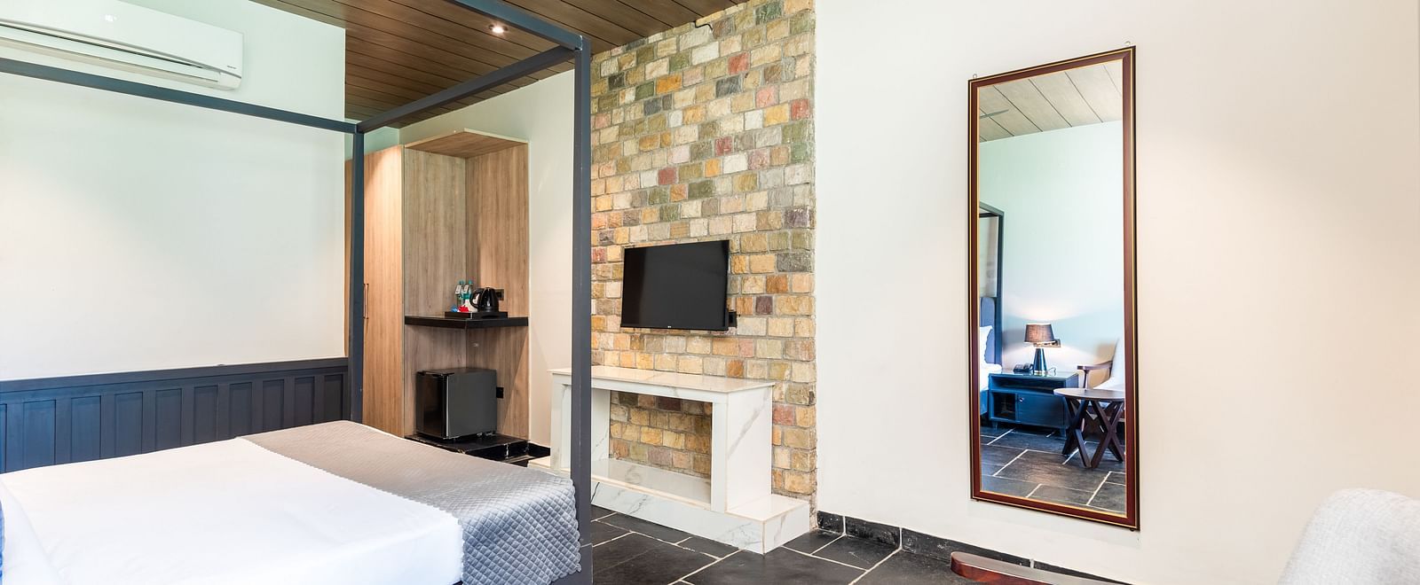 Closeup view of Luxury Cottage at DLS Divine River Resort and  Spa featuring a king size bed with mirror, TV and a chair.
