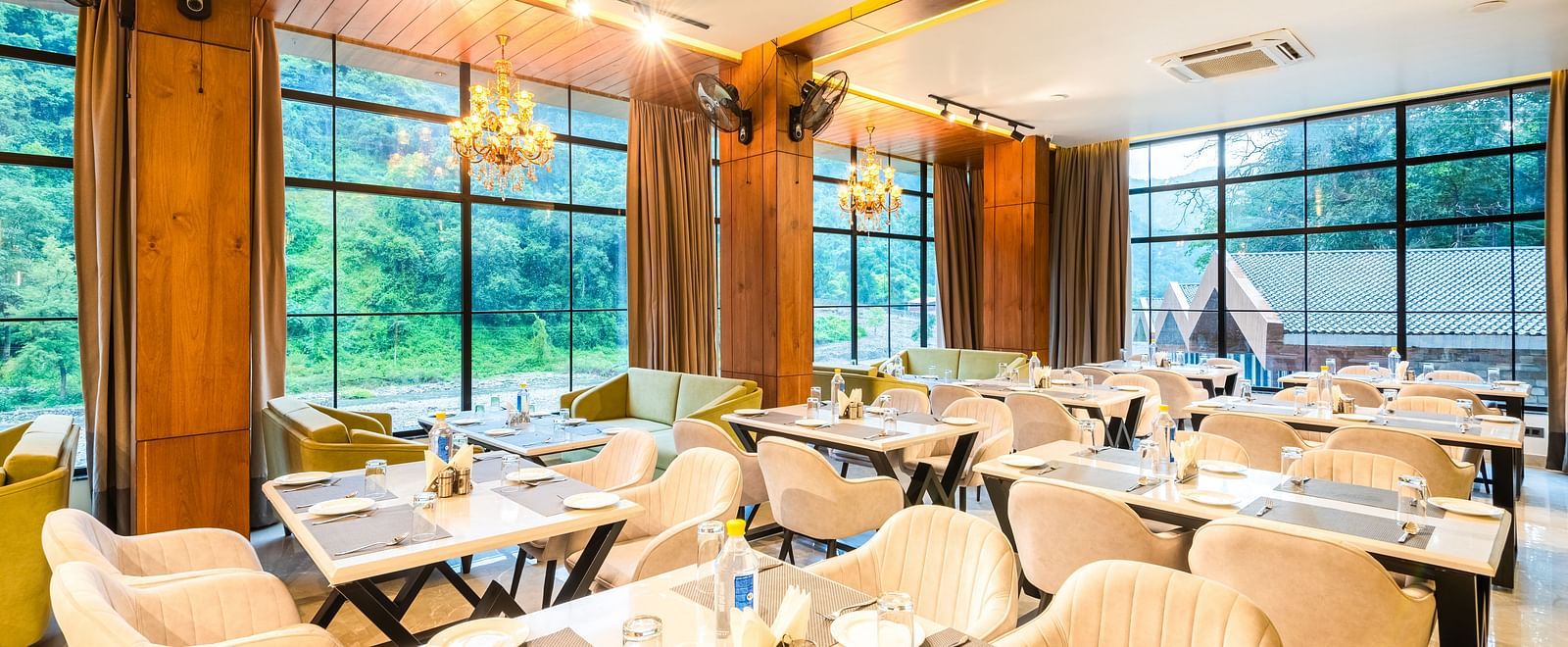Restaurant at DLS Divine River Resort and Spa  with seating arrangement, large window, chandelier and ambient lighting. 