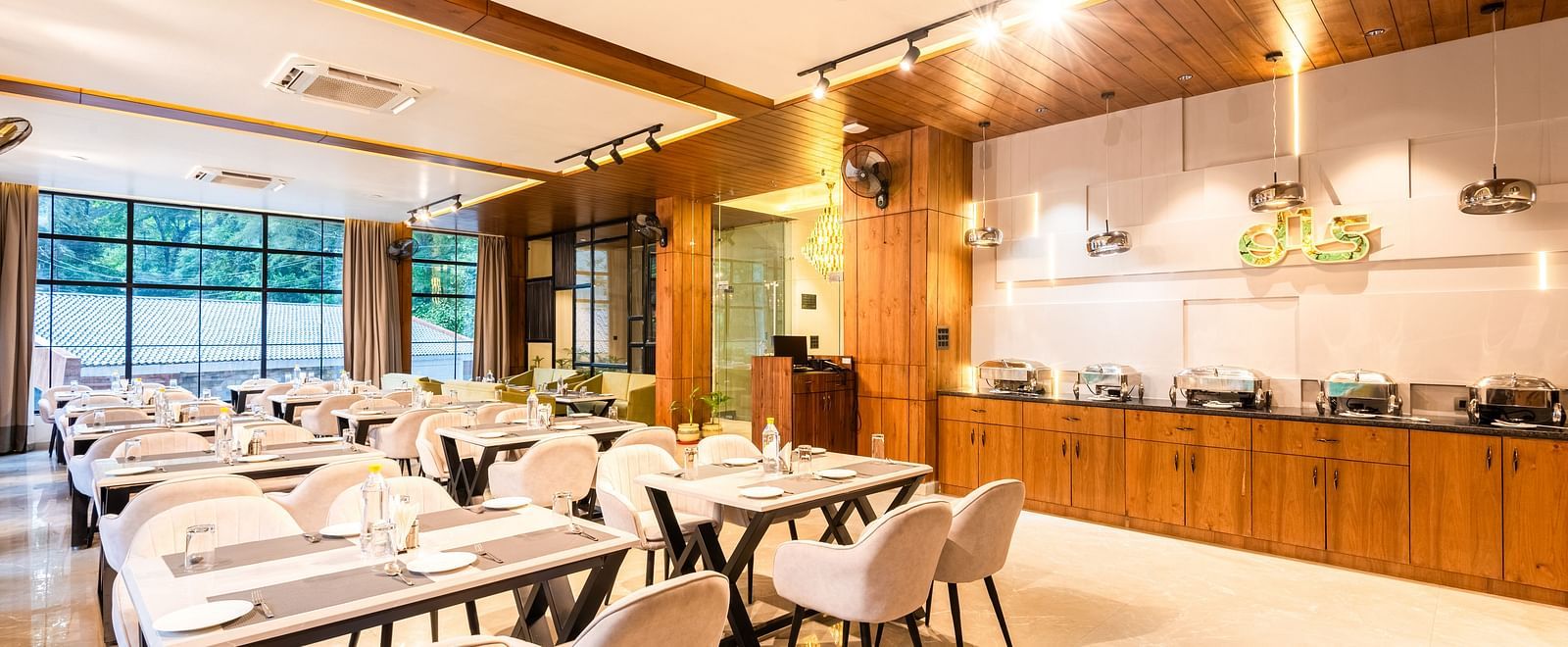 Restaurant at DLS Divine River Resort and Spa  with seating arrangement, large window and ambient lighting. 