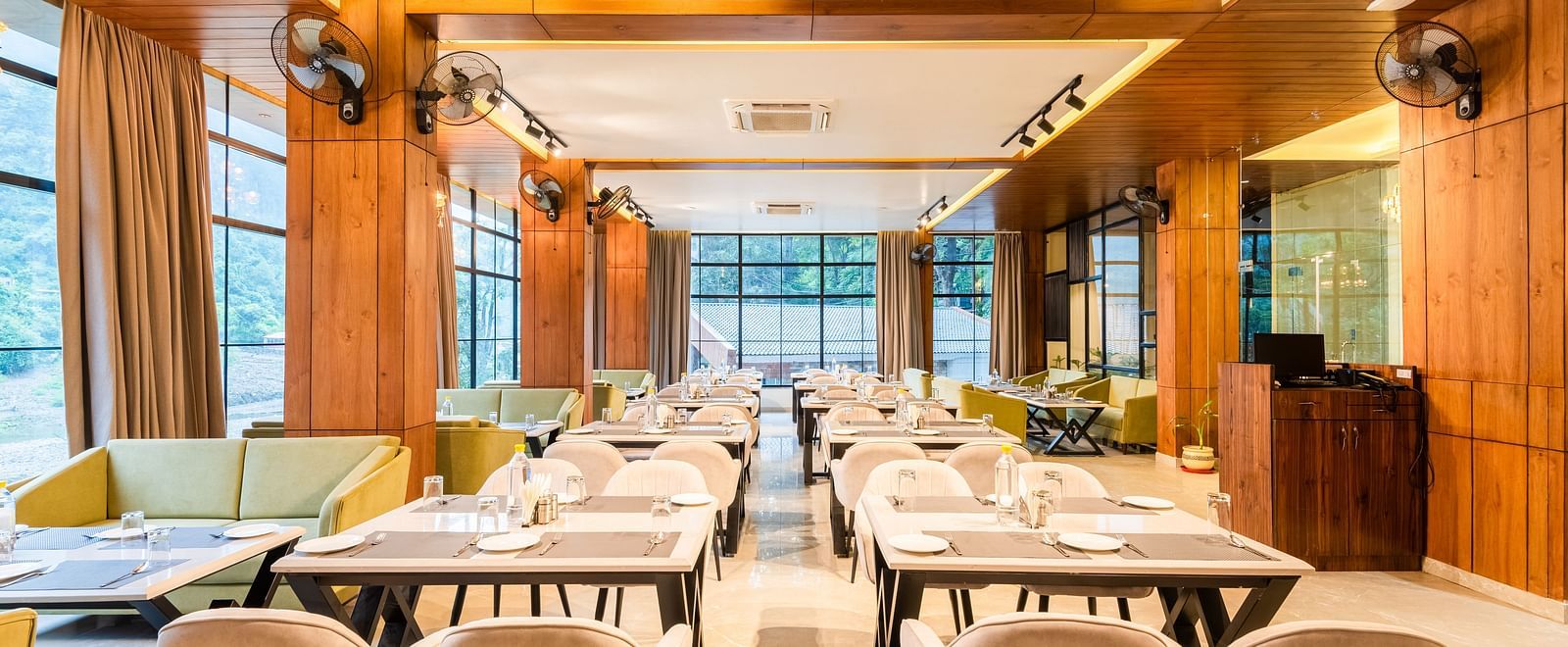 Restaurant at DLS Divine River Resort and Spa  with seating arrangement, large window and ambient lighting. 