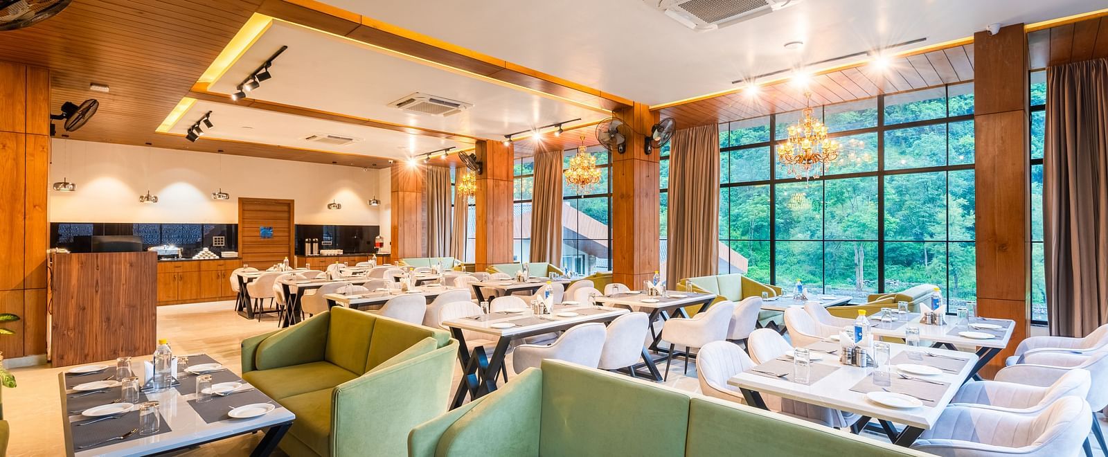 Restaurant at DLS Divine River Resort and Spa  with seating arrangement, large window, green sofa and ambient lighting. 