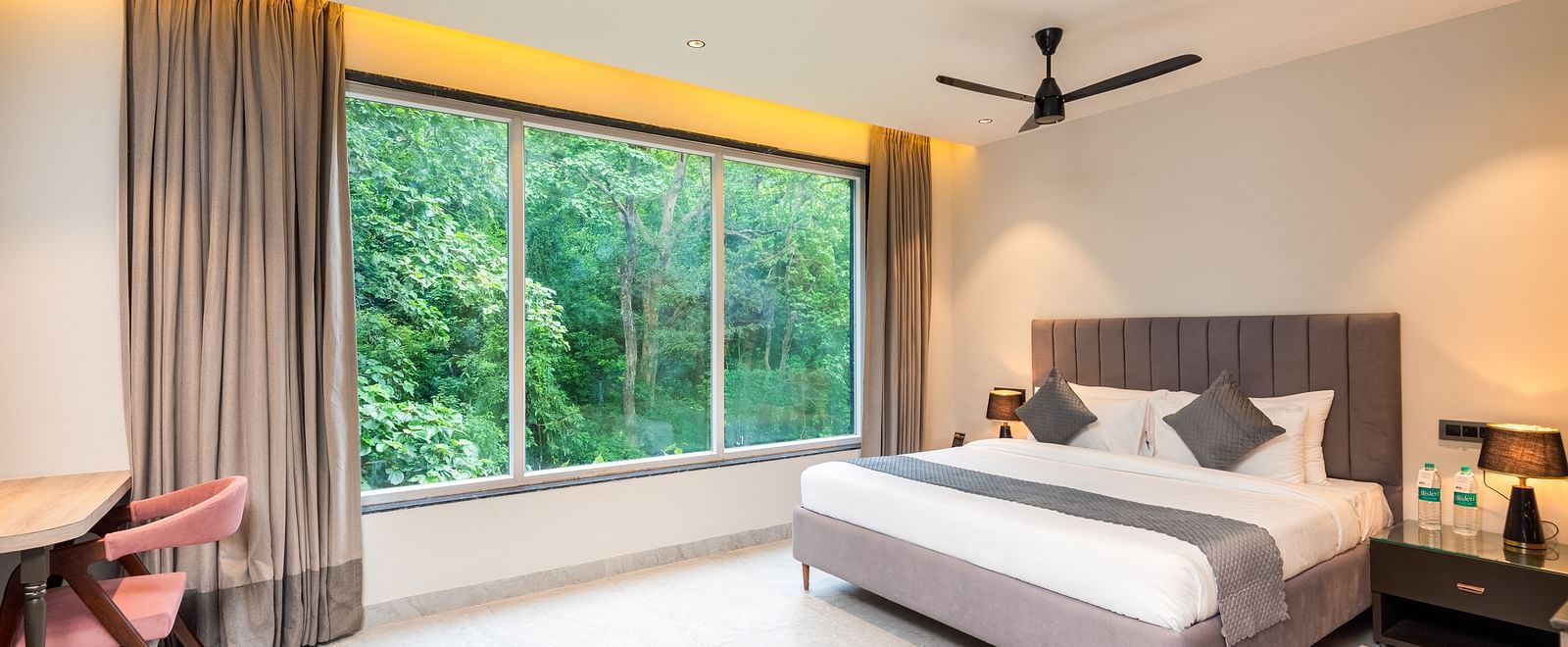 Overview of Deluxe Room at DLS Divine River Resort and  Spa featuring a  king bed , side table, chair and balcony with forest views.