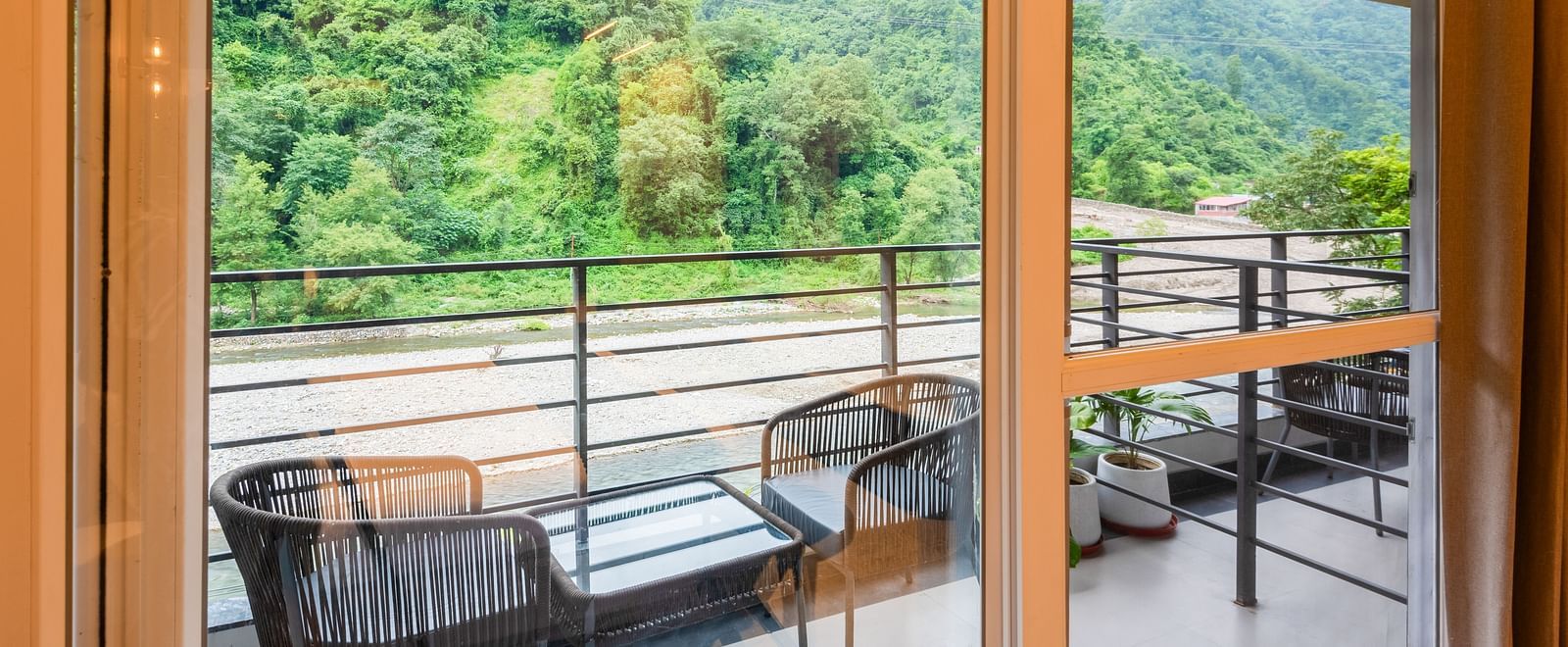 Balcony of Deluxe Room at DLS Divine River Resort and  Spa featuring seating area with forest views.