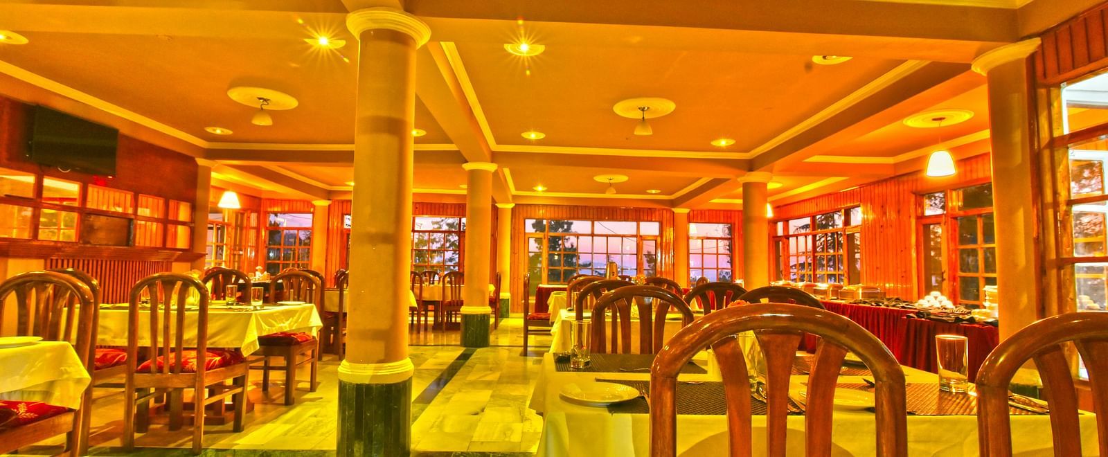 restaurant interior featuring tall pillars with seating arrangements at DLS Hillcrest Resort, Shimla