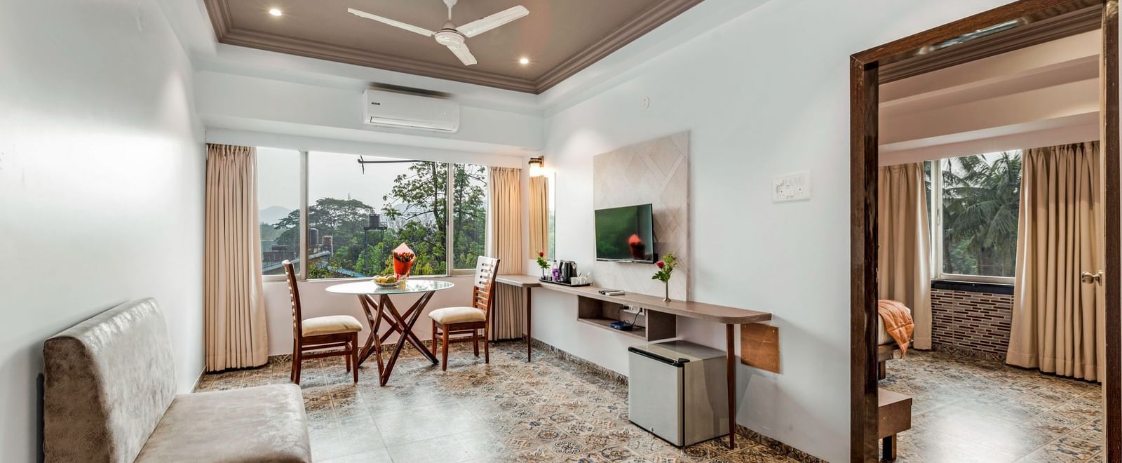 Separate living room at Emerald Retreat, Tungarli featuring a work desk, plush seating, wall-mounted TV, and large windows with scenic views.