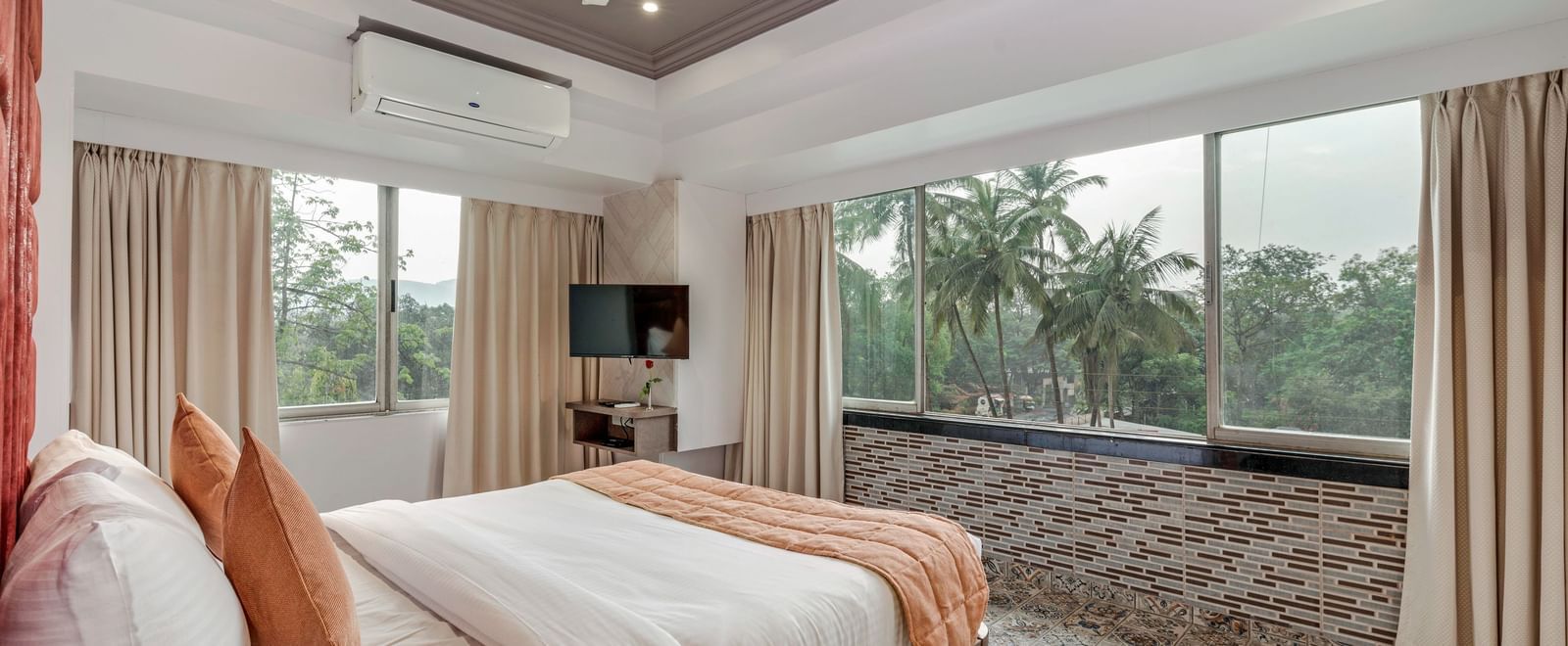 Spacious room at Emerald Retreat, Tungarli with a queen size bed, large windows, and calming garden views.