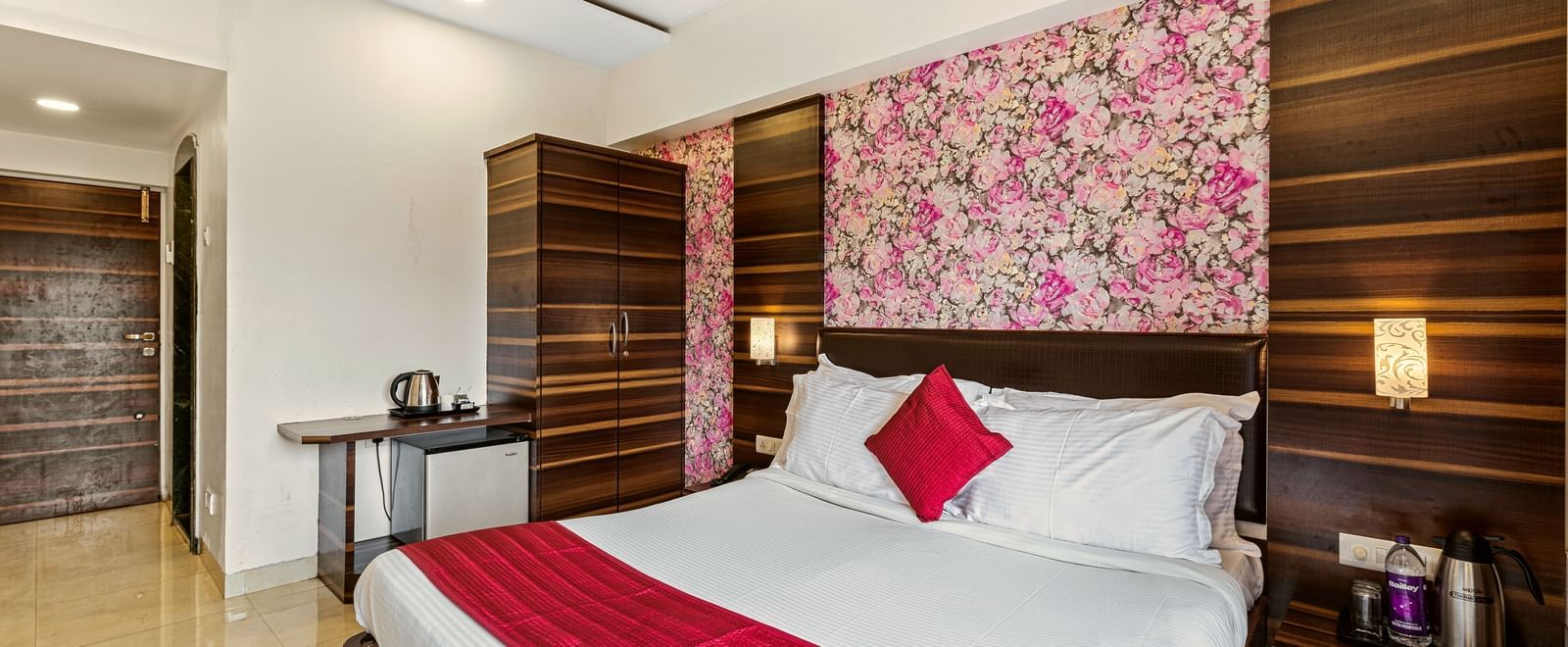 Elegant bedroom at Mayur Retreat with red accents, floral wallpaper, and modern lighting.