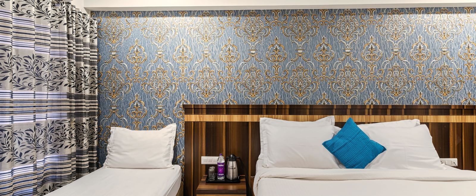 Bright and welcoming bed room with a king size bed and a single bed with vibrant blue accents, traditional wall textures, and a modern atmosphere at Mayur Retreat.