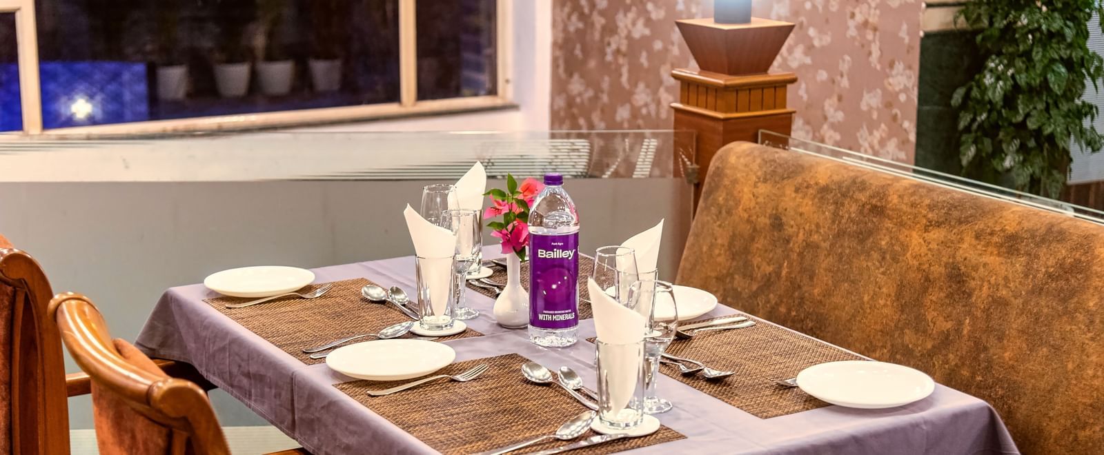 Cosy restaurant seating with a window view, elegantly set tables, and a warm ambience at Mayur Retreat.