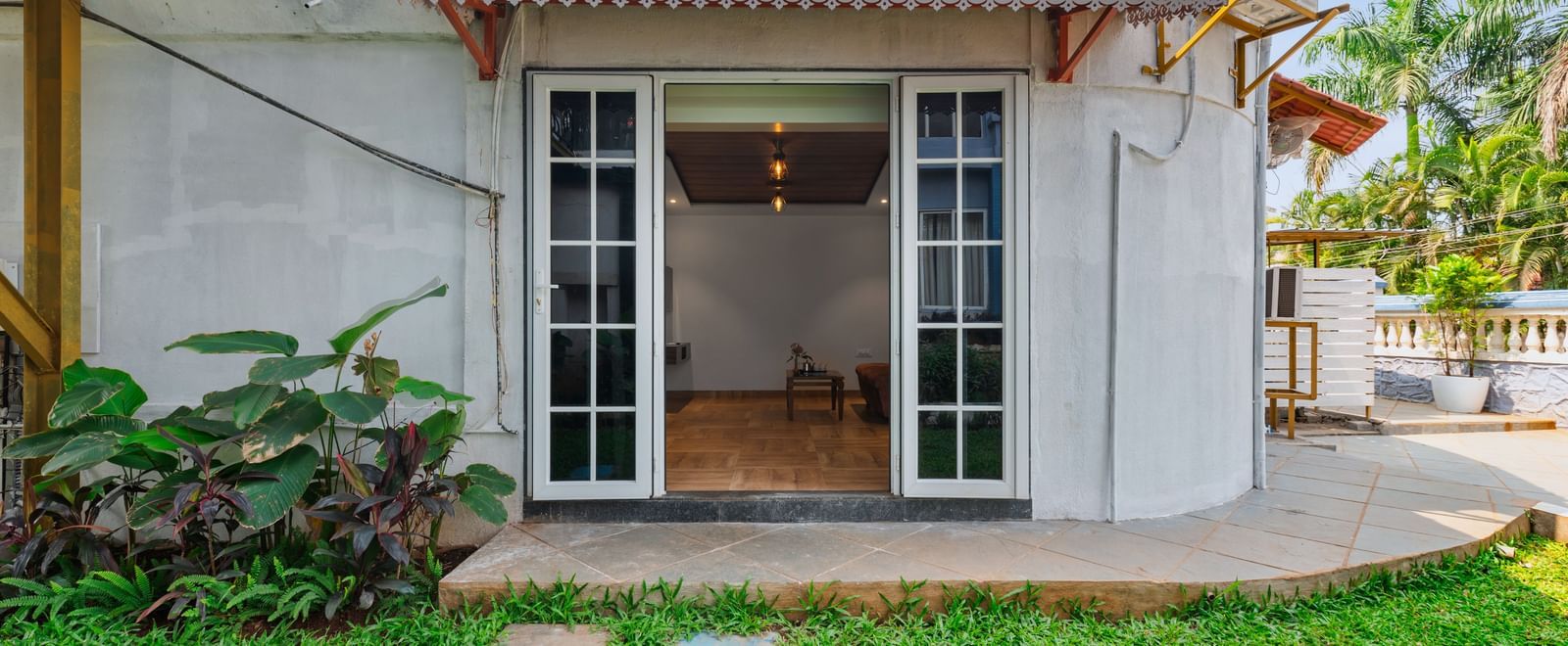 Exterior view of a villa at Mayur Retreat with a private lawn, outdoor seating, and a staircase leading to the upper balcony.