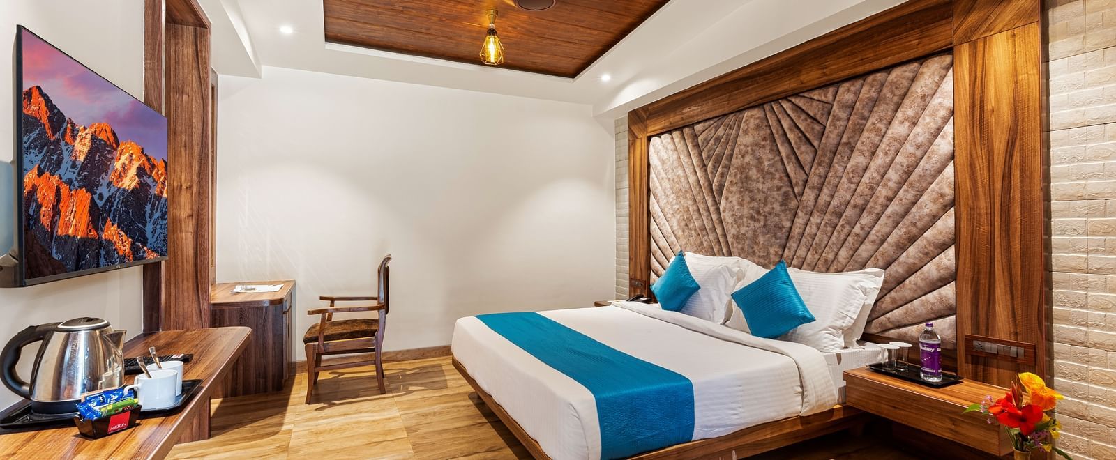 Elegant bedroom at Mayur Retreat with a blue-accented bed, wood interiors, ambient lighting, and a cosy sitting area.