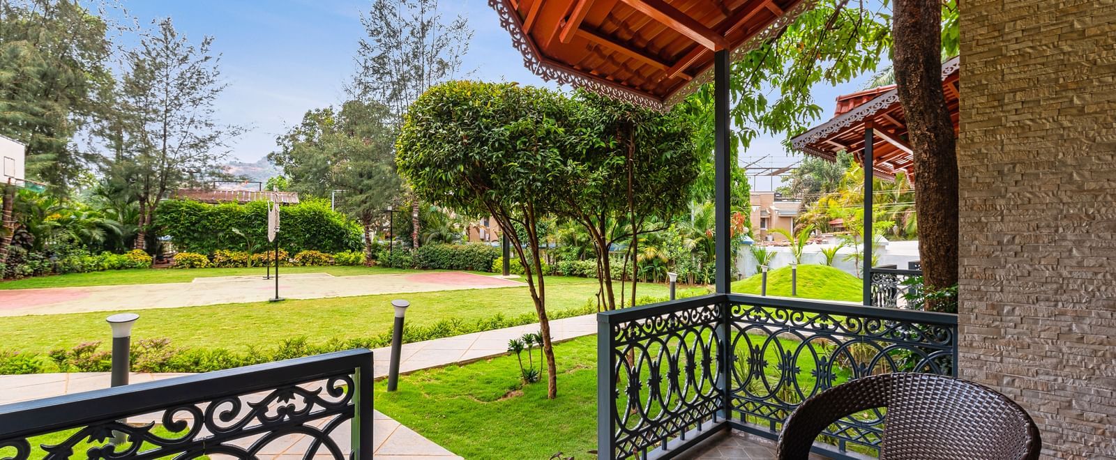 Private balcony with chairs and a table overlooking a lush green garden at Mayur Retreat.