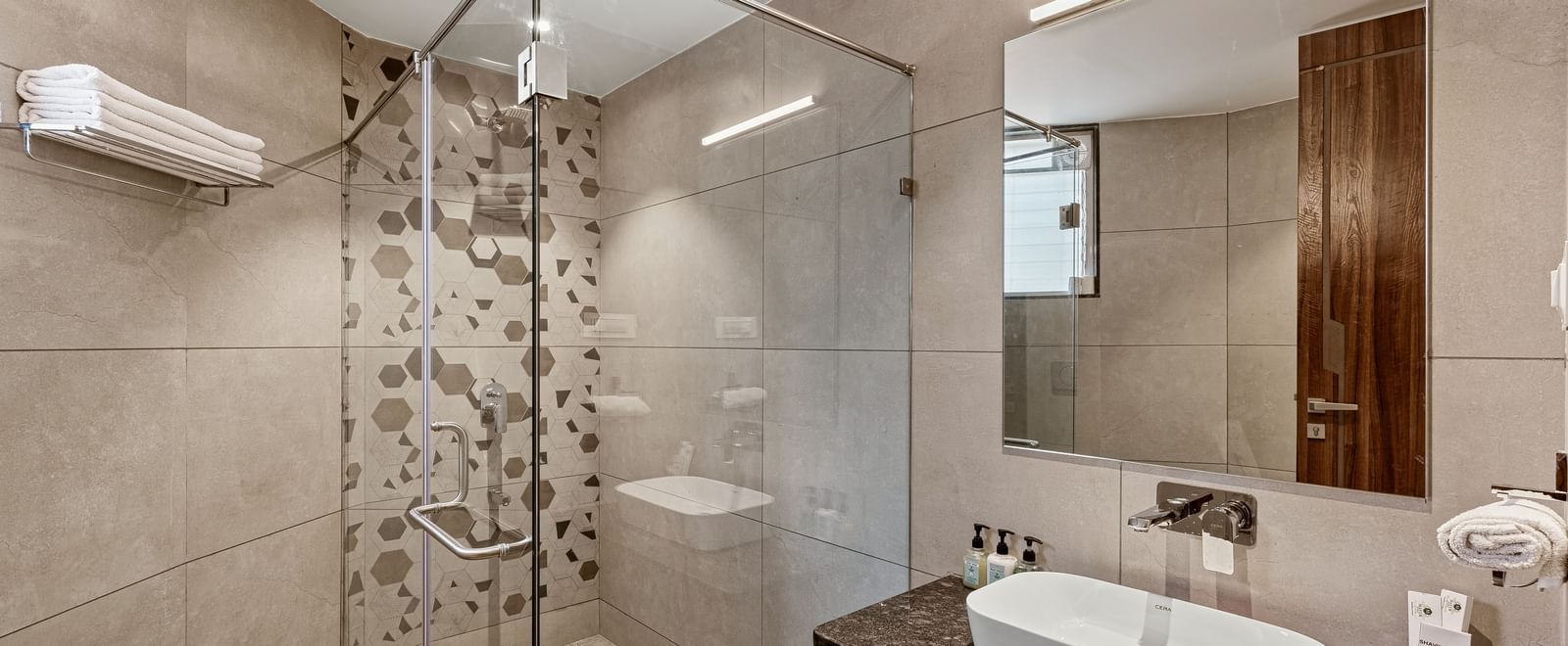 Elegant bathroom with glass-enclosed shower, wall-mounted sink, and modern fixtures at Mayur Retreat.