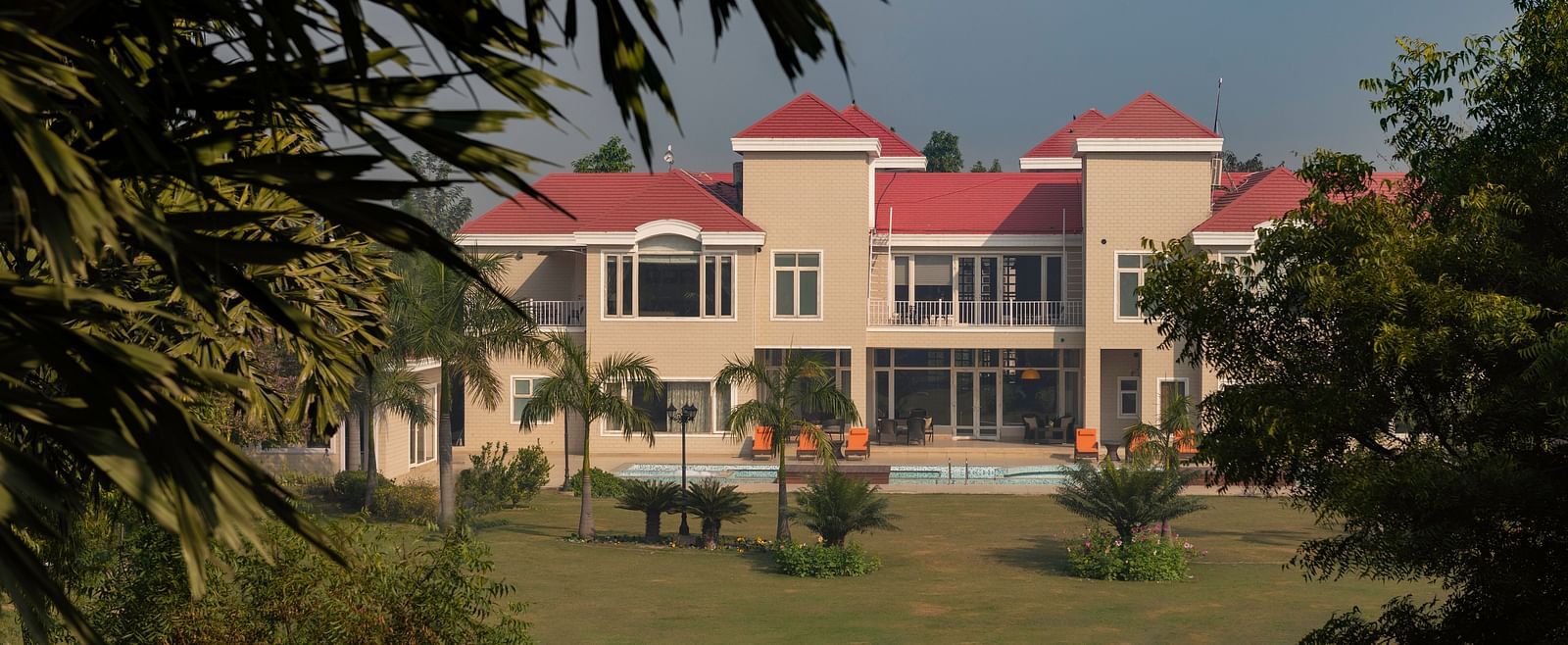 Facade view of BluSalzz Resort with garden and trees in the front.