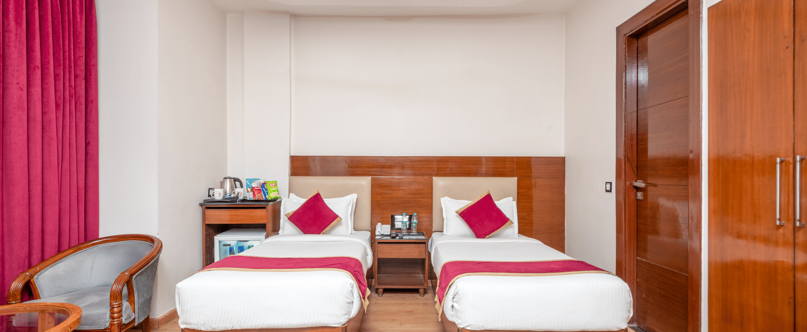 Twin bed room with pink curtains at DLS Hotels On The Ganges.