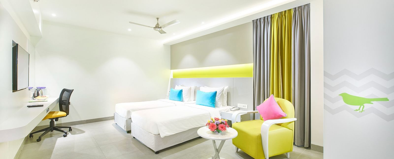 side view of a bedroom featuring a wall-mounted television and a ceiling fan at Zibe Salem by GRT Hotels 