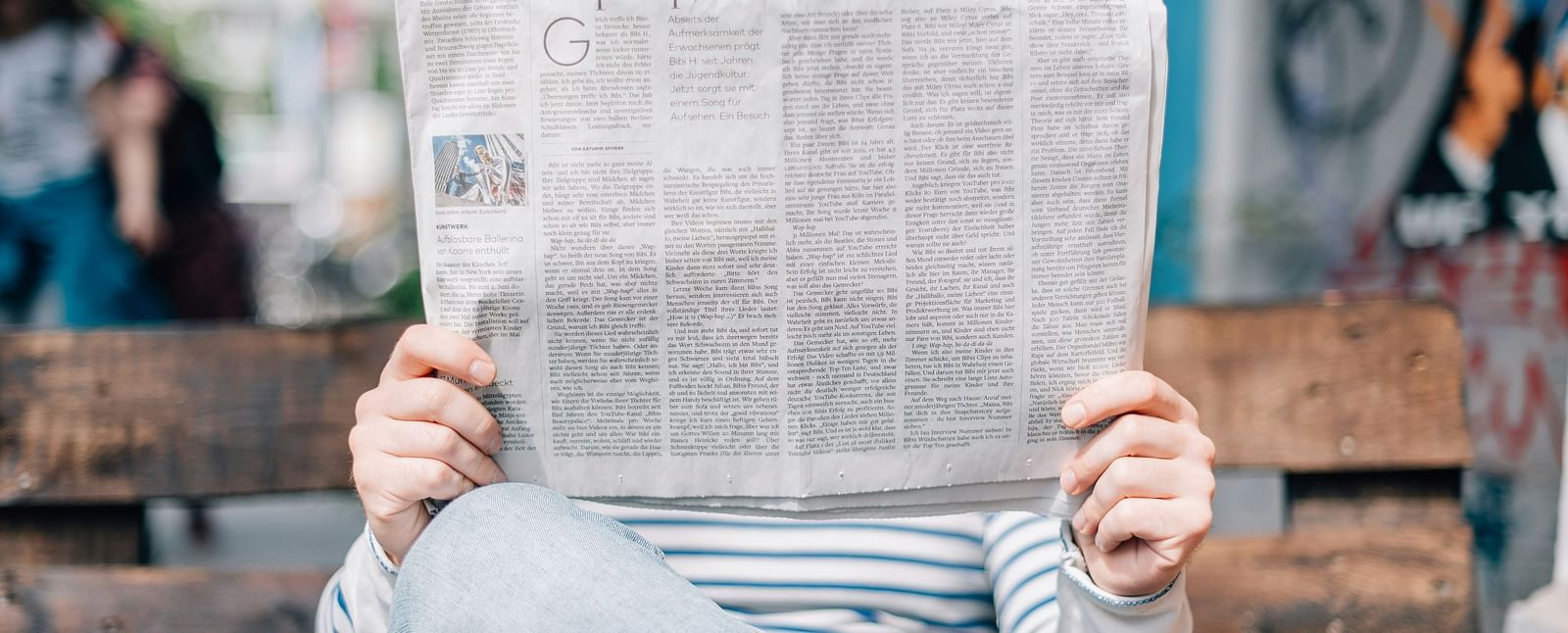 A hidden face behind a crisp newspaper, lost in morning reading