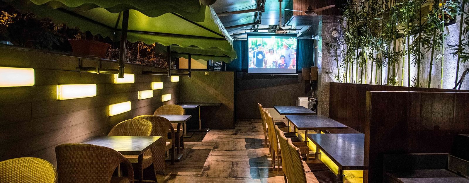 Modern restaurant featuring wooden chairs, tables, and a wall with plants hanging as decoration at Oriental Aster, Mumbai.