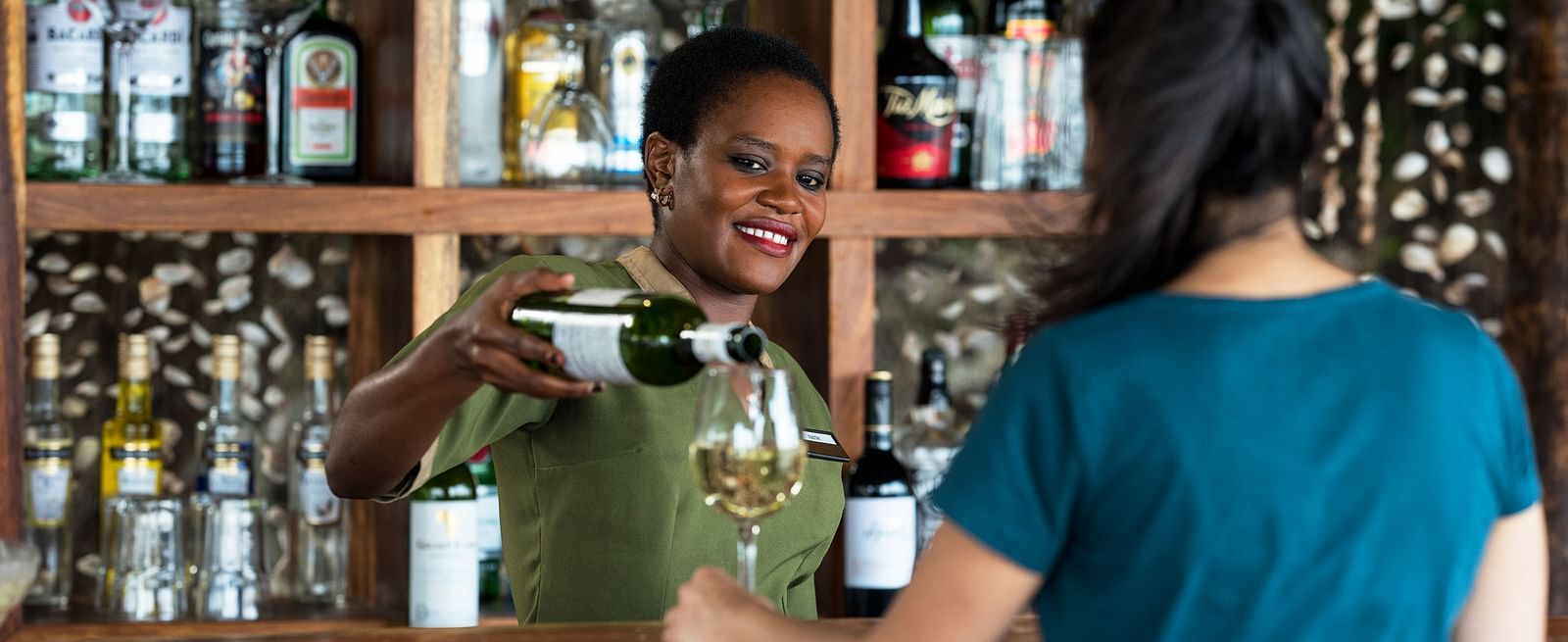 View of a woman poruing a drink in a glass on the counter at Shooting Star Boutique Hotel