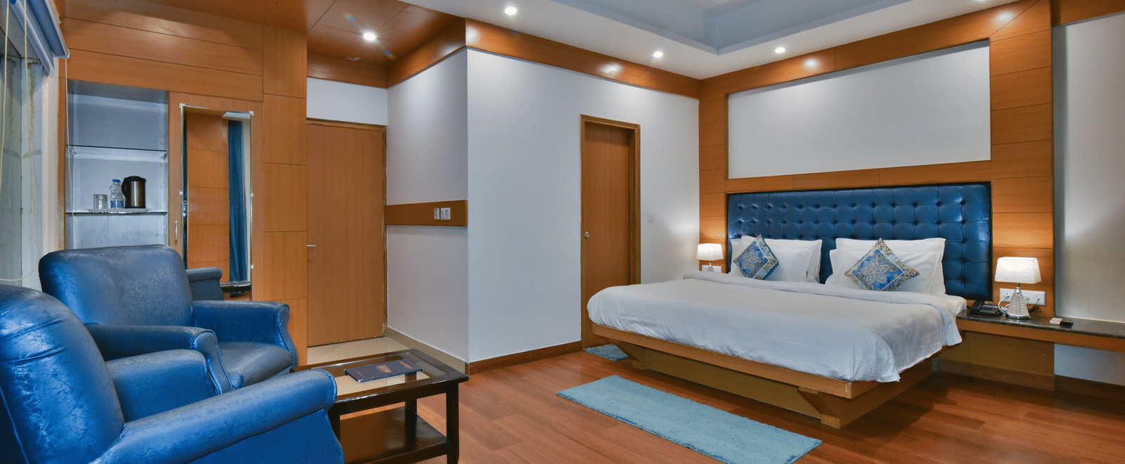 A large bed placed in front of two sofas at the Luxury Room Without Balcony at DLS Highland Resort and Spa, Mussoorie.