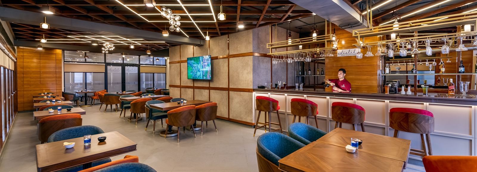 Interior of a Distil bar with wooden accents, blue chairs, and warm lighting labeled 'Distil Bar'