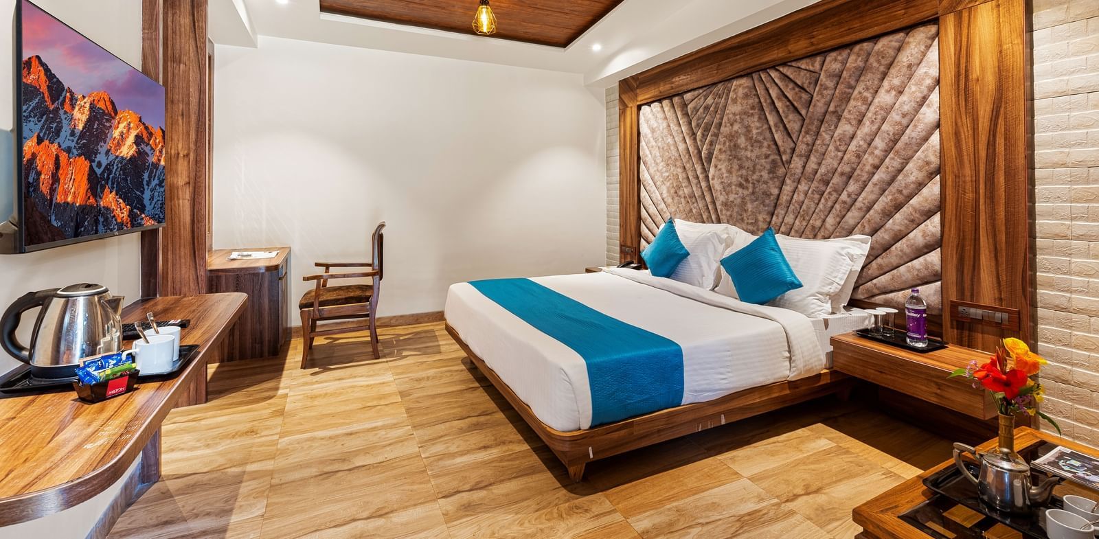 Elegant bedroom at Mayur Retreat with a blue-accented bed, wood interiors, ambient lighting, and a cosy sitting area.