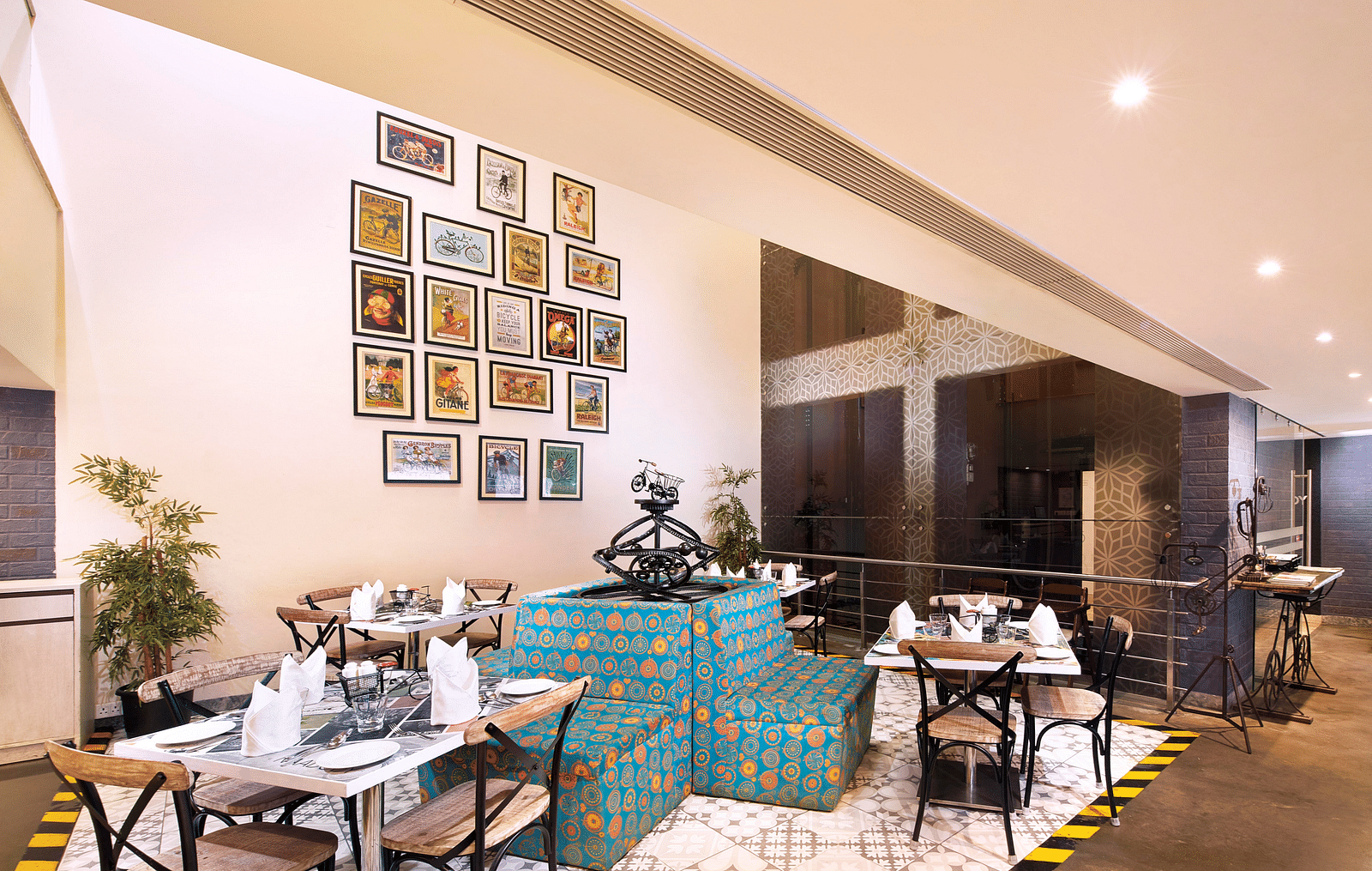 A brightly lit restaurant with blue couches and a colorful wall mural | Regency Tirunelveli By GRT Hotels