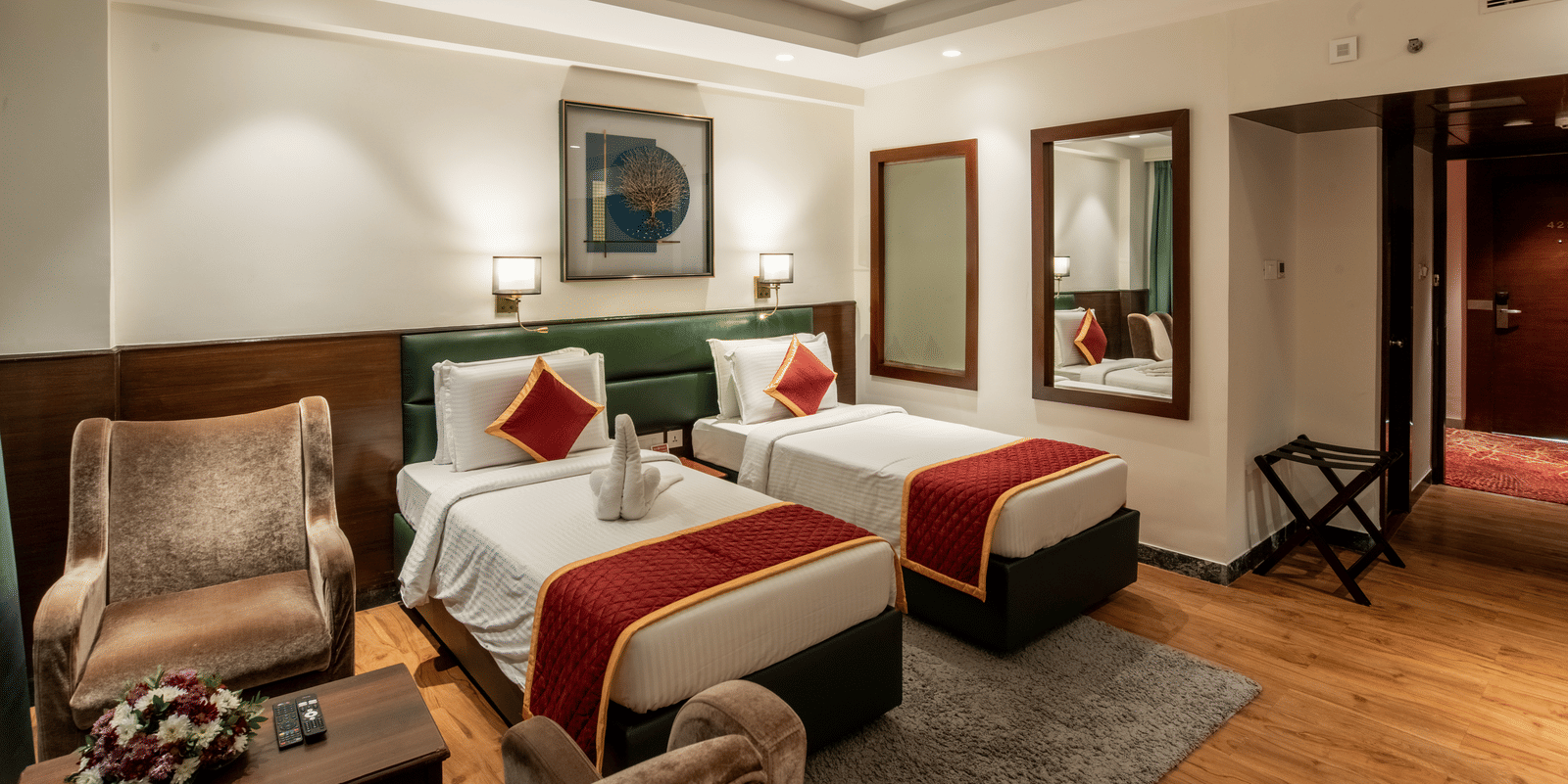 Twin bedroom with stylish decor, armchair, and framed artwork at Hotel Royal Regency Chennai
