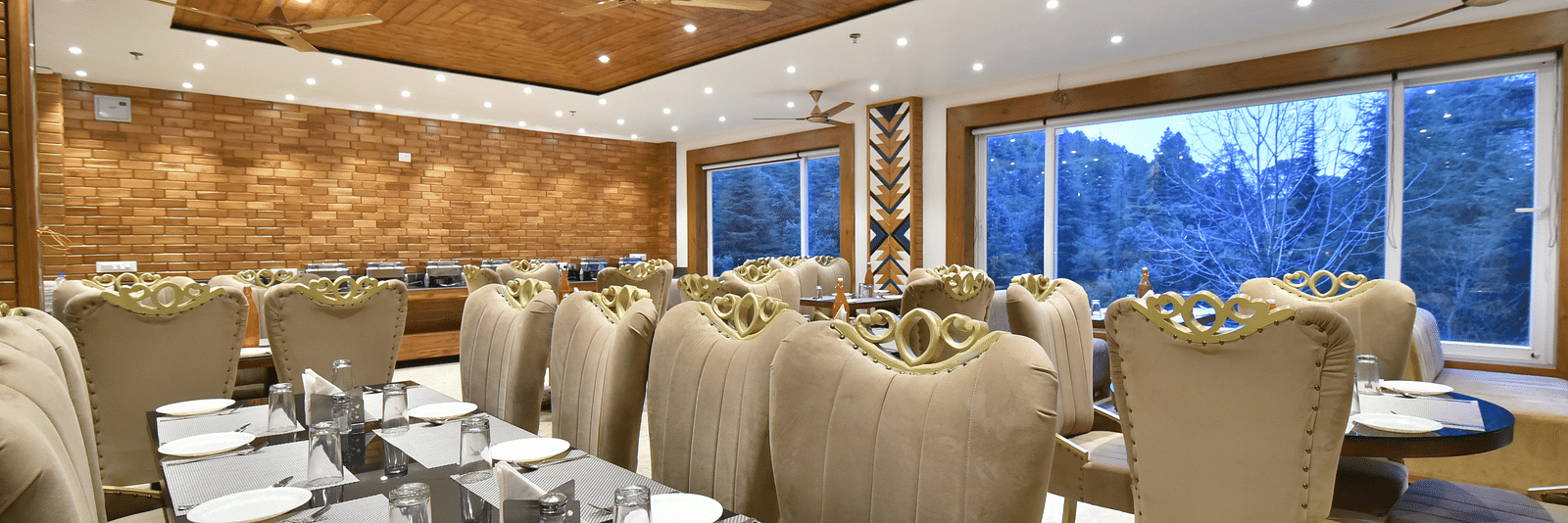 Dining area with comfortable chairs around tables at Rainbow Restaurant at DLS Ark Holiday Inn, Banikhet.