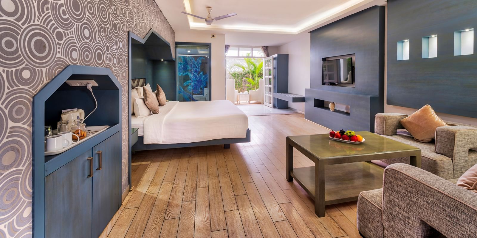 A spacious hotel suite featuring a bedroom area with a large bed and a separate living area with a sofa and coffee table | Grande Chalet | Grande Bay Resort & Spa, Mamallapuram