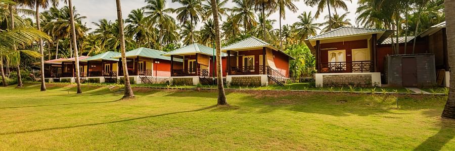 sunny day image with red huts accommodation - Ibex River Resort, Pollachi